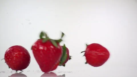 Strawberries Rolling left to right on white surface, in slow motion. Stock Footage 61643173
