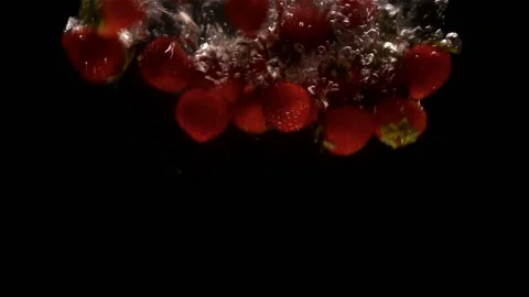 Strawberries in slow motion falling into water on a black Stock Footage 137168604