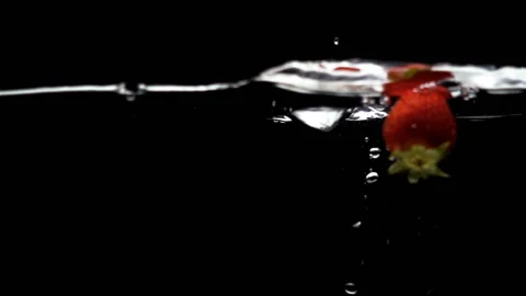 Strawberries in slow motion falling into water on black Video stock 138989076