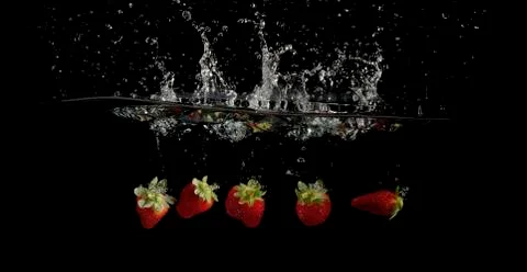 Strawberries splashed into water 写真素材