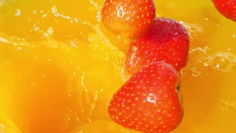 Strawberries splashing into orange juice, creating vibrant waves and bubbles Stock Footage 288114849