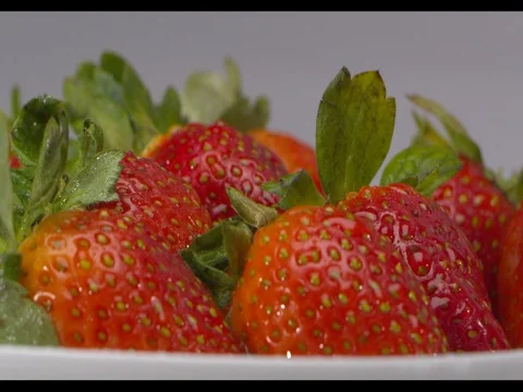 Strawberries on a white plate being sprayed with water, medium shot, slow motion Stock Footage 74198091