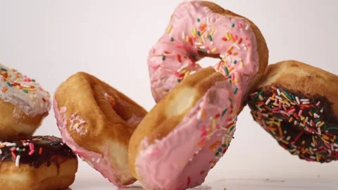 Strawberry and chocolate sprinkle donuts bouncing on white slow motion macro Видео 337037665