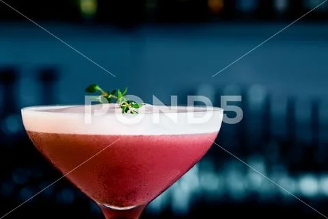 Strawberry cocktail on the bar counter. With background in shades of blue and Stock Photos