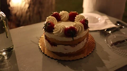 Strawberry cream cake on table at warm evening party Stock Footage 337729029