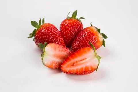 A strawberry cut in a half in front of three entire strawberries Stock Photos