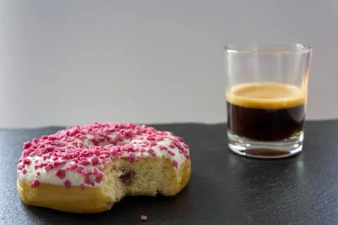 Strawberry Donut with Bite Missing and a cup of espresso coffee Foto stock