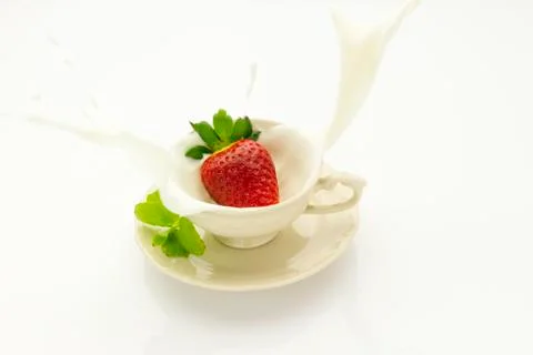 Strawberry falling into cream Stock Photos