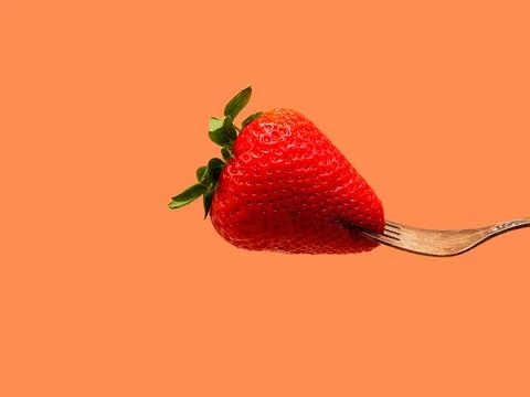 Strawberry on fork on orange background Stock Photos
