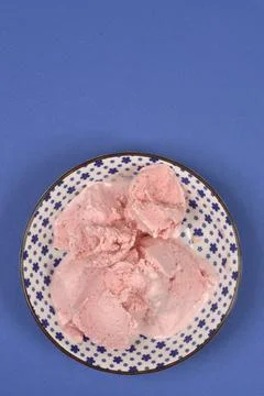 Strawberry ice cream in a blue patterned bowl on blue background Stock Photos