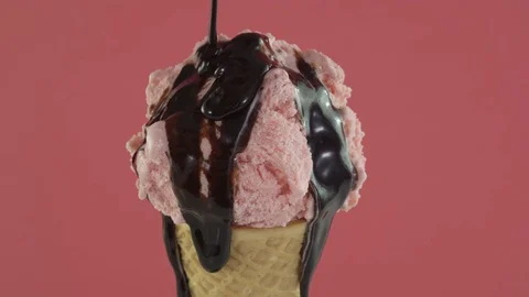 Strawberry ice cream with chocolate sauce in waffle cone on pink background Stock Footage