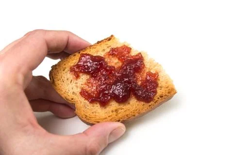 Strawberry jam on cracker slice in hand on white background Stock Photos