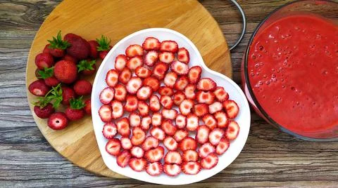 Strawberry slices on a white plate in the shape of a heart. Kluunichny puree Stock Photos