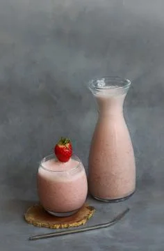 Strawberry smoothie in a glass and glass bottle, light gray background Stock Photos
