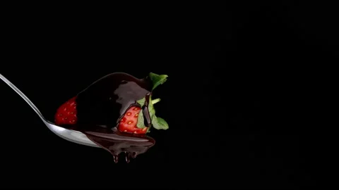 Strawberry in the spoon on black background, covered by chocolate. Stock Footage 150114906