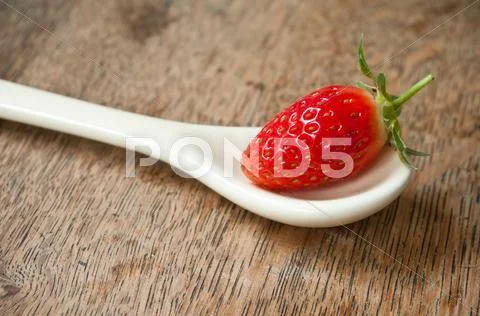 Strawberry in a spoon on wooden table background Stock Photos