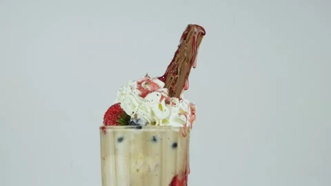Strawberry syrup drips down as chocolate flakes are sprinkled on top of a Vidéo 134653561