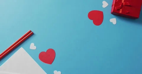 Straws with paper hearts and present on blue background at valentine's day Stock Footage 342017623