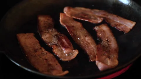 Streaky bacon rashers frying in a cast iron skillet Stock Footage 132505494