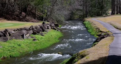 Stream along asphalt paved path flowing toward camera. Stock Footage 276905346