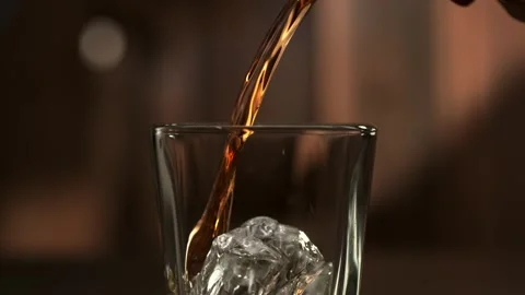 Stream of Amber Whiskey Poured over an Ice Cube. Stock Footage 271007127