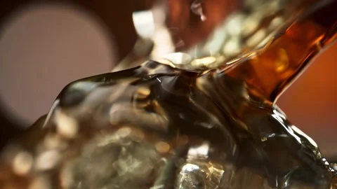 Stream of Amber Whisky Flowing Smoothly over an Ice Cube in Macro &amp; Slow Motion Stock Footage 271007390