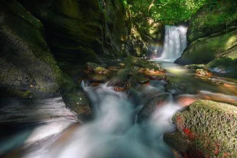 Stream and waterfall with small rainbow between eroded limestone cliffs Stock Photos