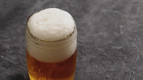 Stream of beer pours into a rotating Stock Footage 243595758