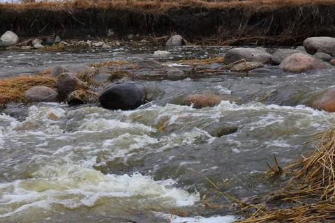 A stream between rocks and dry grass Fotos de archivo