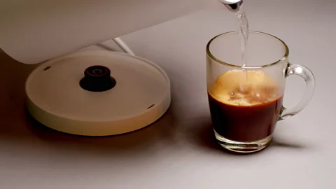 A stream of boiling water is poured from a kettle into a mug with coffee Stock Footage 150759790