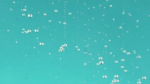Stream of bright red ink flushing into sparkling water over cyan background Stock Footage