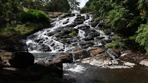 A stream cascading over a steep rock formation to a pool below Stock Footage 265832848