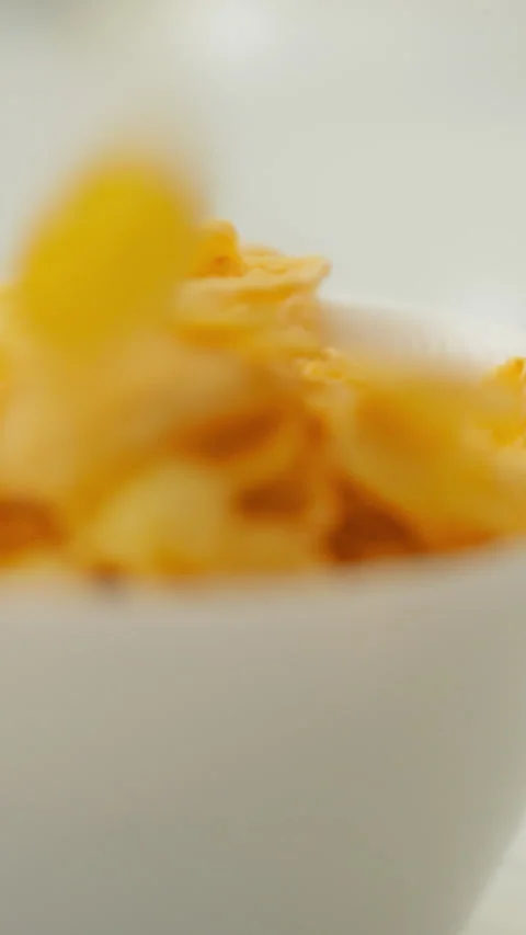 A stream of cereal pours into a clean white bowl on a table with a separate Stock Footage 341283501