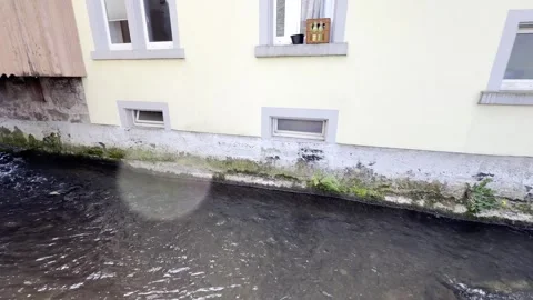 A stream channeled by stone walls flows past houses in Höllstein, Germany Stock Footage 338050771