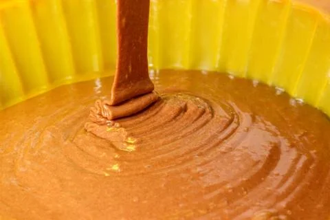 A stream of chocolate dough filled into a baking dish Stock Photos
