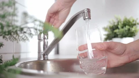 A stream of clean water drink flows into the glass. Woman holding a glass of Stock Footage 197115731