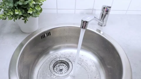 A stream of clean water drink flows from the kitchen faucet into the stainless Stock Footage 197115851