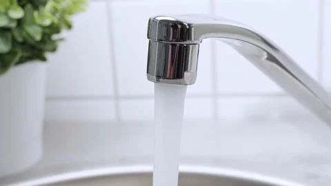A stream of clean water drink flows from the kitchen faucet into the stainless Stock Footage 197700814