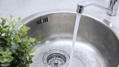 A stream of clean water drink flows from the kitchen faucet into the stainless Stock Footage 197701378