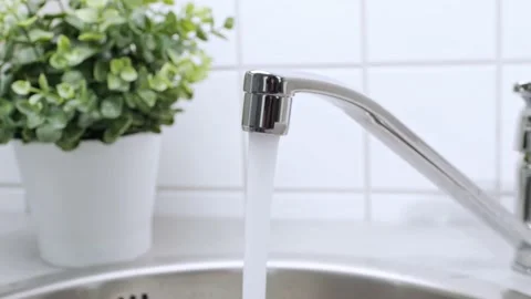 A stream of clean water drink flows from the kitchen faucet into the stainless Stock Footage 203524045
