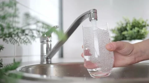 A stream of clean water drink flows into the glass. Woman holding a glass of Stock Footage 209630048
