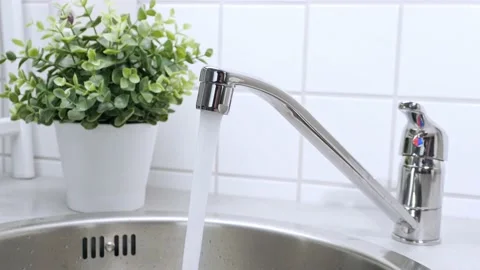 A stream of clean water drink flows from the kitchen faucet into the stainless Stock Footage 209630253