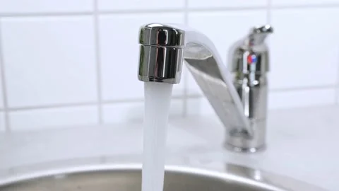 A stream of clean water drink flows from the kitchen faucet into the stainless Stock Footage 226211893