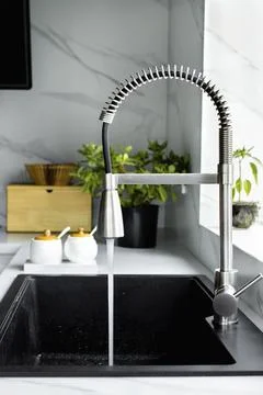 A stream of clean water drink flows from the kitchen faucet into the sink Stock Photos