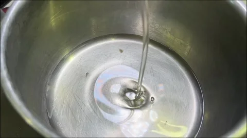 Stream of clear oil being poured into a stainless steel pot, reflecting lig.. Stock Footage 314218339