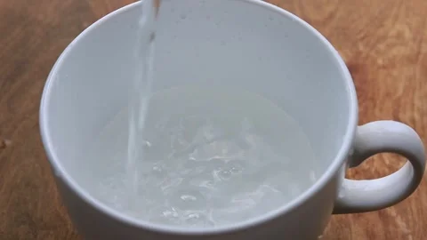 Stream of clear water flows into a white porcelain cup Stock Footage 340141828