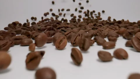 Stream of coffee beans moving to a camera on a white background. Slow motion Stock Footage 148196291