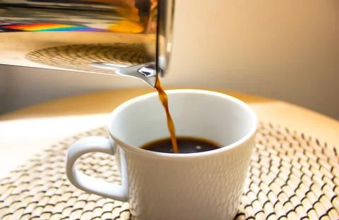 Stream of coffee filter. A process of pouring black beverage into white cup. Stock Photos