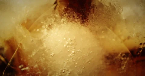 A stream of Cola flows into a glass with ice cubes. Cola with ice and bubbles Stock Footage 263333595