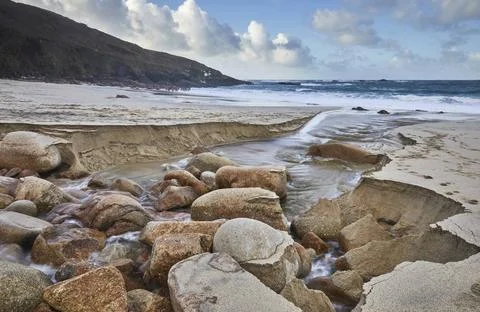 A stream cuts through sand and rocks as it makes its final dash to the sea... Stock Photos